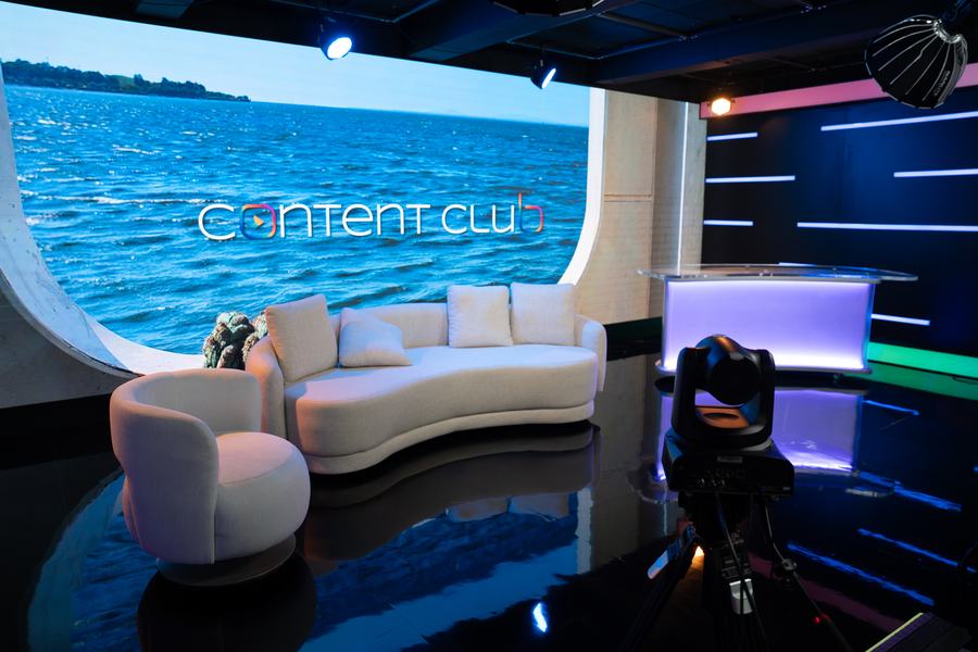 Parede de LED curva exibindo cenário virtual, com piso espelhado e desk de apresentação